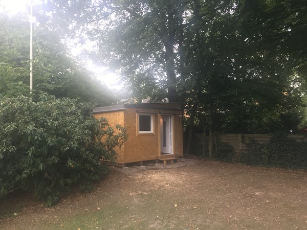 View of the shed from a few meters away – with a new step in front of the door.