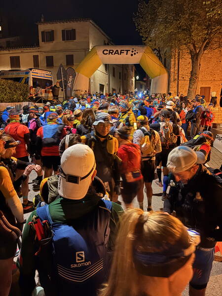 Lots of people in running gear standing in front of a start line arch in the dark – I’m into this eery atmosphere