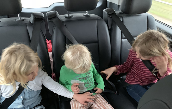 The big sisters helping the little sister to fasten her seat belts in a Brussels taxi